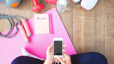 Woman in active wear with mobile device. Home training with smart devices