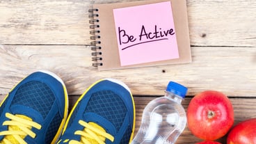 Words Be Active on a piece of paper with sports shoes, apples and a bottle of water Sports equipment