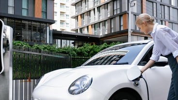 Progressive businesswoman plugs charger plug from charging station to EV