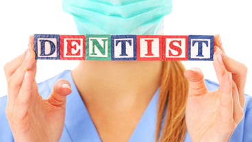 doctor's hands showing a dentist text on wooden blocks over white background