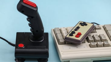 Retro gamepad and joystick with PC keyboard on a blue background. Video game, 80s games.