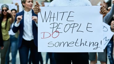 Unrecognizable black man holding placard with White people do something inscription while taking a part in Black Lives Matter protest