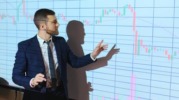 Young Businessman Explaining Graphs To His Colleagues On Projector