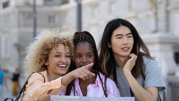 Group of young multiethnic smiling tourists visiting city of Madrid and pointing with a finger