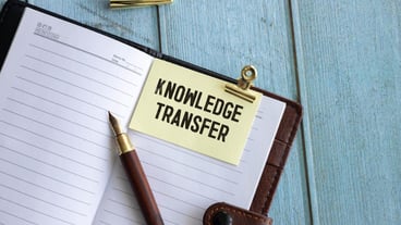 Knowledge transfer text with magnifying glass on blue background