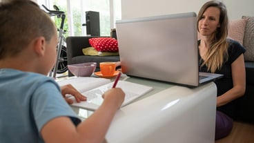 Tired young mother working from home while also homeschooling her son in a global epidemic.