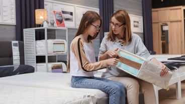 Mature woman and her daughter examining orthopedic mattress sample, shopping for furniture