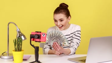 Woman holding dollar banknotes recording video to subscribers talking with followers