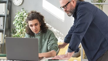 Mature teacher talking to his student and explaining the material on laptop during lesson