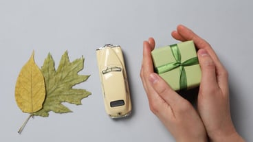 Retro toy car with gift and leaves from above