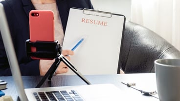Woman hands holding resume application near her workplace with laptop.