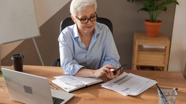 Confident stylish european middle aged senior woman using smartphone at workplace stylish older matu