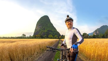 the cyclist with the bike in a field watching the sunset sports and hobbies outdoor activities