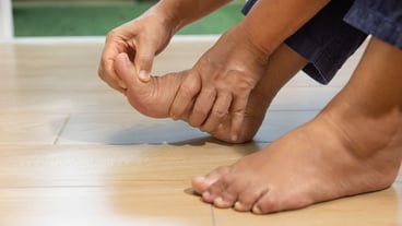 Elderly man massaging his foot with swollen gout inflammation