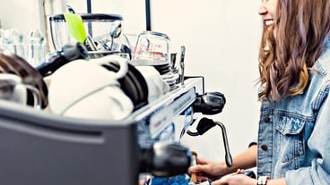 Barista prepares coffee at the coffee machine at the café counter