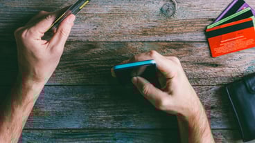 Hombre Manos sosteniendo tarjeta de crédito y usando teléfono móvil.