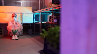 Full length portrait of female scientist wearing full protective gear sitting on floor in bio laboratory lit by UV light, copy space