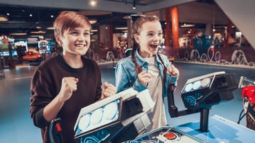 Boy and girl are piloting blue spacecrafts playing in arcade