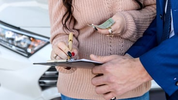 Dealer and customer signing contract on clipboard