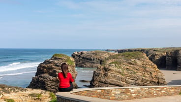 Woman looking at the landscape of the beach of the cathedrals in galicia spain - Playa de las Catedrales