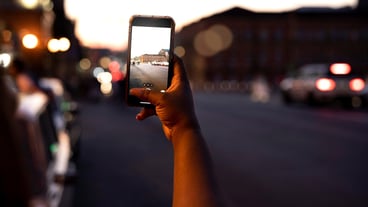 Woman taking photo at night in the city lights with smartphone