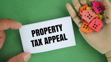 in hand there is a house form and paper with the word Property Tax Appeal