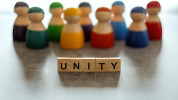 UNITY word on wooden blocks with a group of people in the background