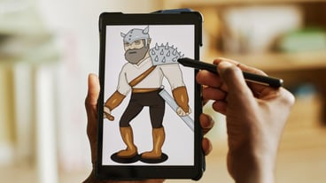 Tablet with graphic image of warrior on screen in hands of african american designer using stylus wh