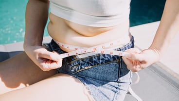 femme grosse, ventre rond, femme obèse, main tenant un mètre ruban, concept de régime et de mode de vie féminin