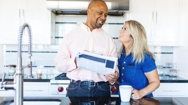 A couple in a modern kitchen smiling and enjoying coffee The man holds a tablet Bright kitchen happy couple coffee time modern kitchen setting Couple are happy in modern kitchen