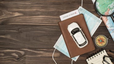 Overhead photo of brown passport with covid19 test inside car mask map magnifier compass notepad pen and glasses isolated on the wooden backdrop with blank space