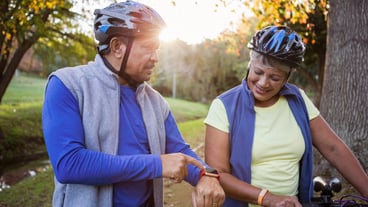 Man pointing his smart watch front of his wife