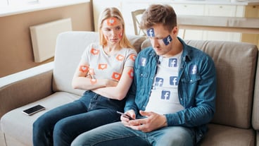 Young man and young woman addicted to social media. Concept of smartphone addiction. Angry woman on the couch.