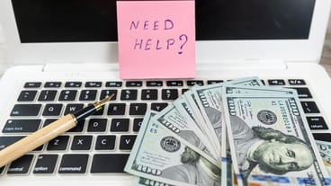 Laptop note with text Need help and dollar cash as idea for investment