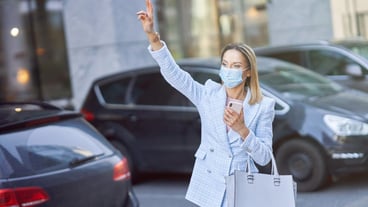 Business woman in mask catching a taxi in the city. High quality photo