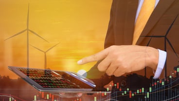 Digital composite image of businessman using digital tablet with wind turbines in background