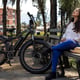 Young Latin American woman 33 is sitting resting on a bench in the square next to her electric bicycle Concept means of transport and spring