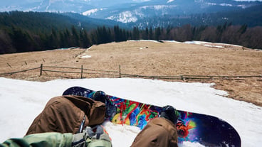 Snowboarder legs and bright blue snowboard in white snow beautiful winter landscape background