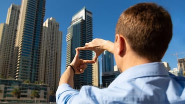 Rear view of man using mobile phone against buildings in city