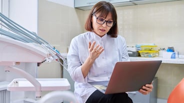 Online consultation doctor help in clinic using laptop Female dentist talking looking in laptop in dental office Video conference videocall service dentistry medicine technology concept