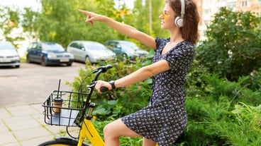 Ecological transport concept: cute European girl rides a rental bike in a city park and shows the direction