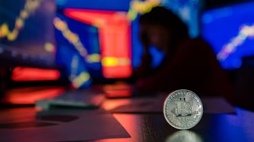 Close up shot of silver bitcoin cryptocurrency virtual token on desk with unhappy failure trader