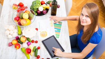 A young adult woman informing herself with a tablet PC about nutritional values of fruits