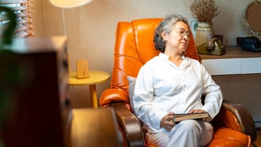 Happy Asian senior mature woman wearing glasses napping on sofa in living room after reading a book Elderly retired grandmother enjoy indoor lifestyle with leisure activity and hobbies at home