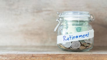 Coins and dollar bills in glass jar with retirement label