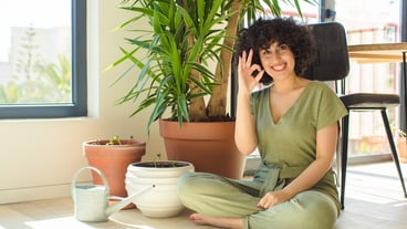 Young pretty woman at home, with a watering can and plants