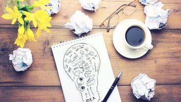 Cup of coffee, pen, notepad, papers, glasses and flowers on wooden table