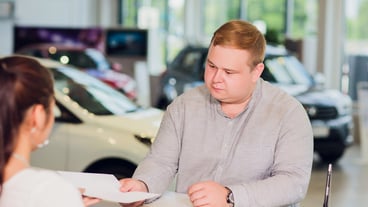 Successful businessman in car dealership - sale of vehicles to customers