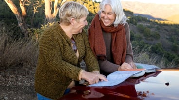 Two senior women consulting a map while out for a nature trip