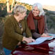 Two senior women consulting a map while out for a nature trip